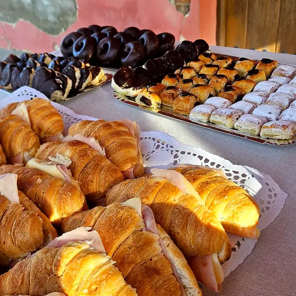 Desayuno de catering con croissants de jamón y queso y bollería variada